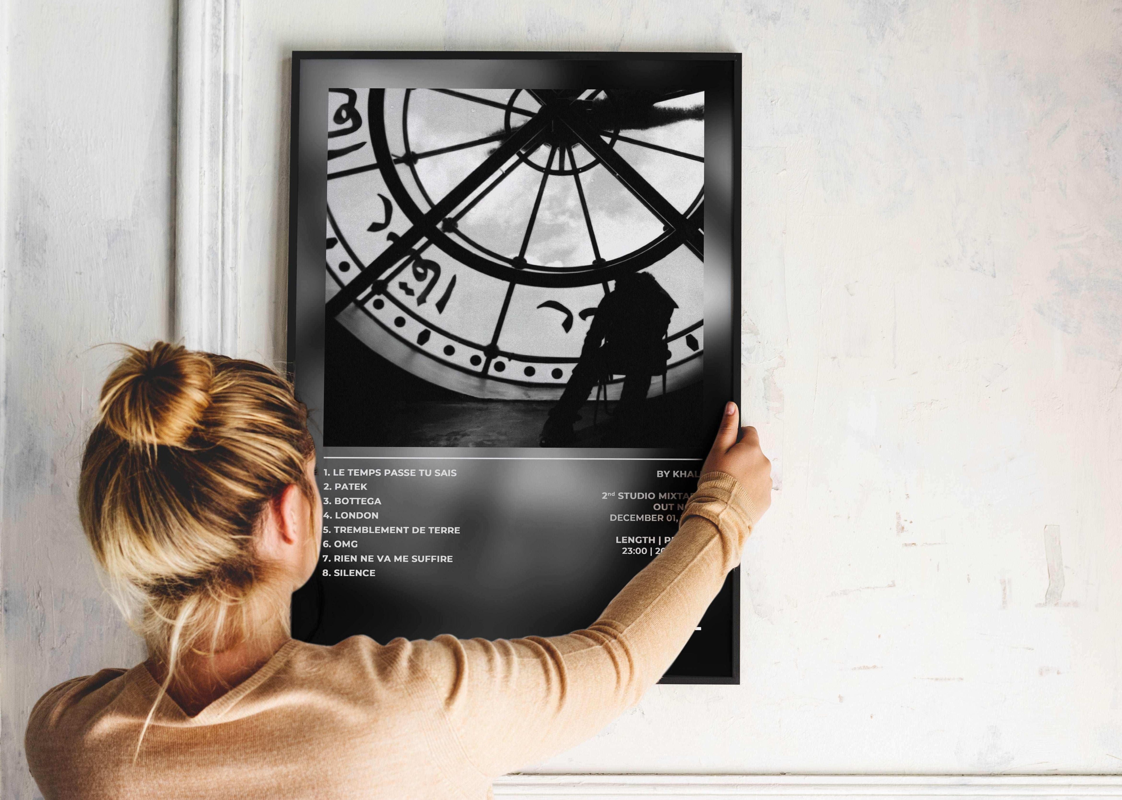 Femme accrochant une affiche noire, silhouette devant une grande horloge, fait en France, livraison gratuite 48h, cadeau idéal pour Noël.