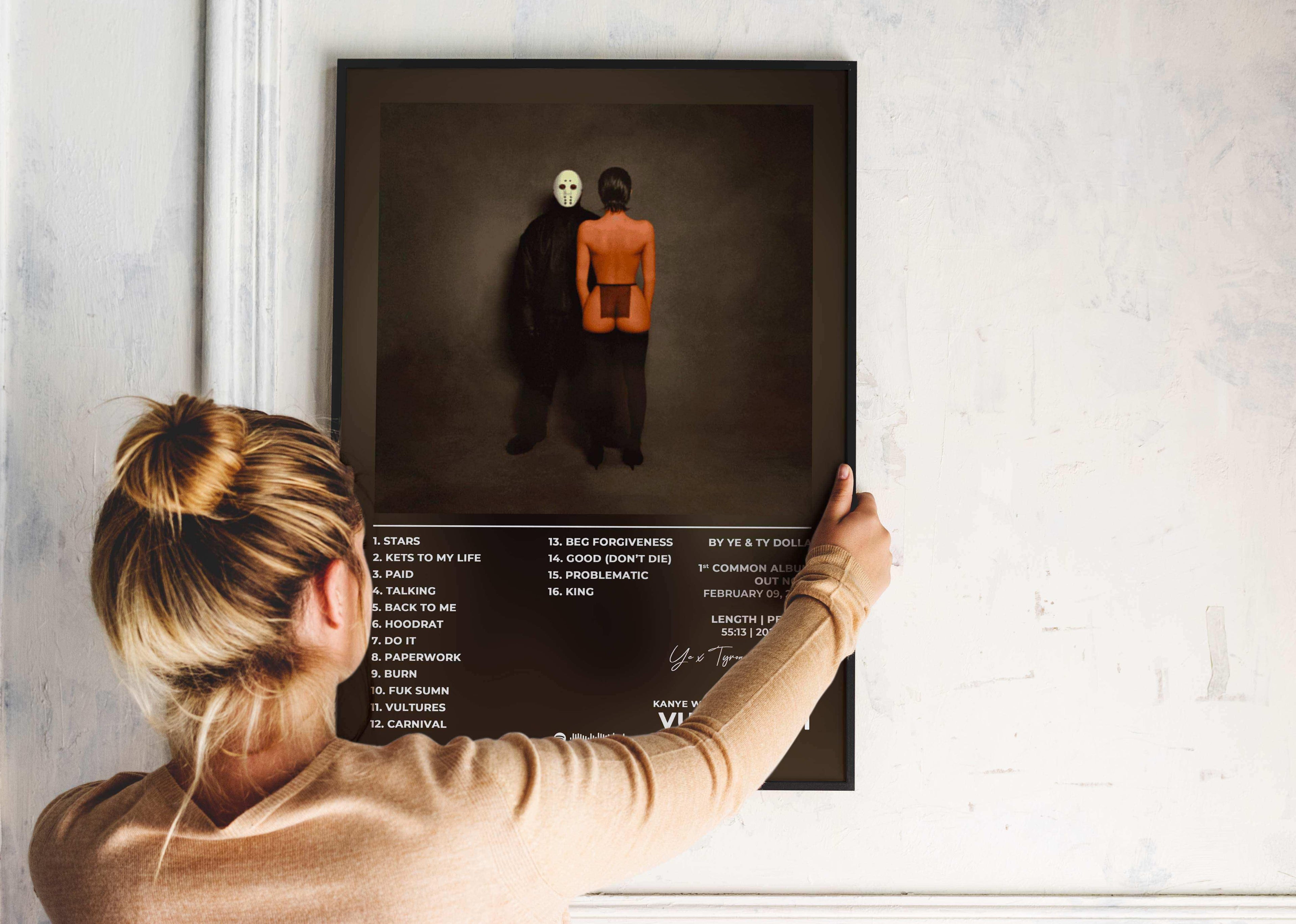 Femme accrochant un poster album sur un mur blanc, fait en France, livraison 48h gratuite, cadeau idéal pour Noël.