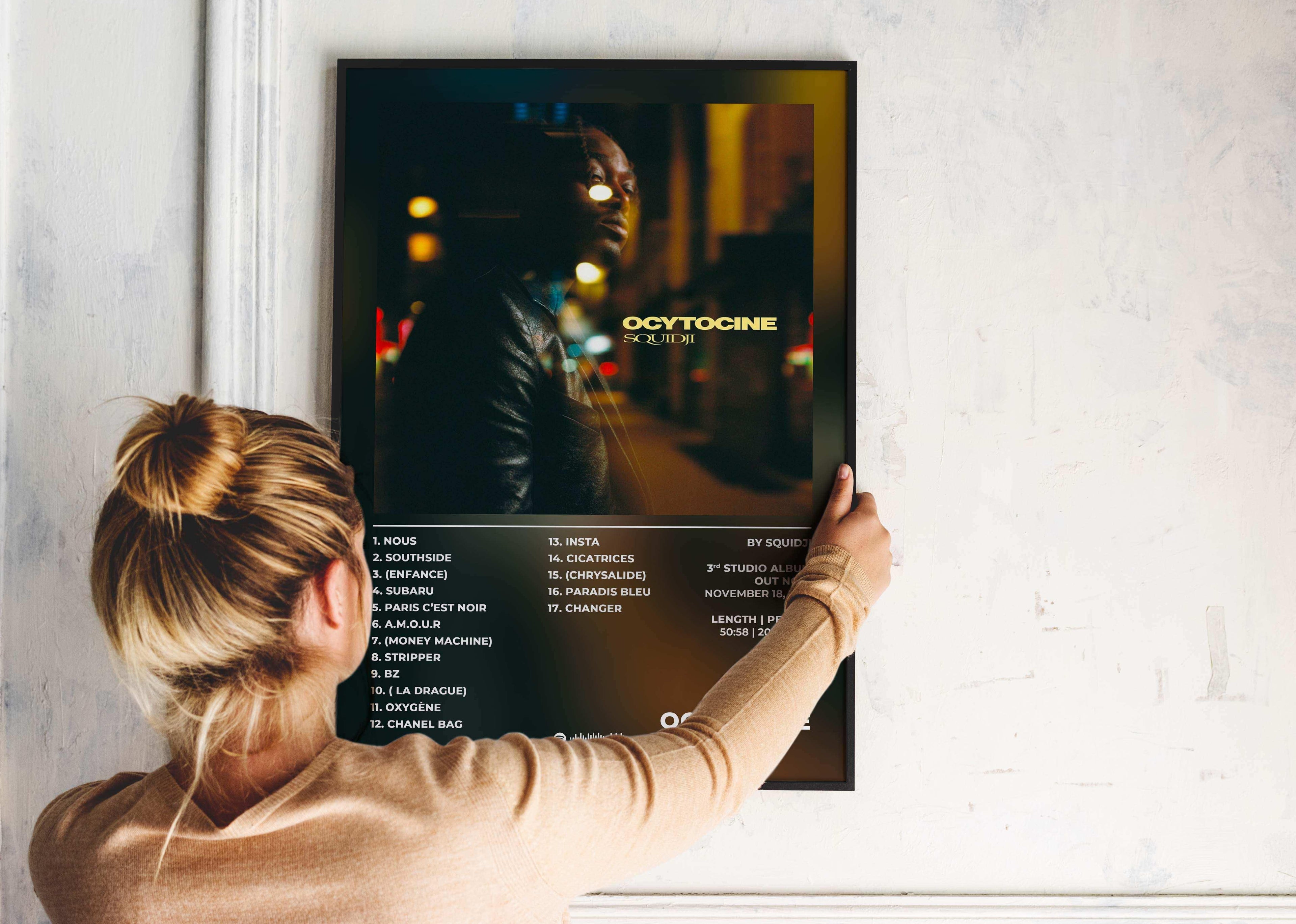 Femme accrochant un poster album Oxytocine, fait en France, livraison gratuite 48h, cadeau Noël
