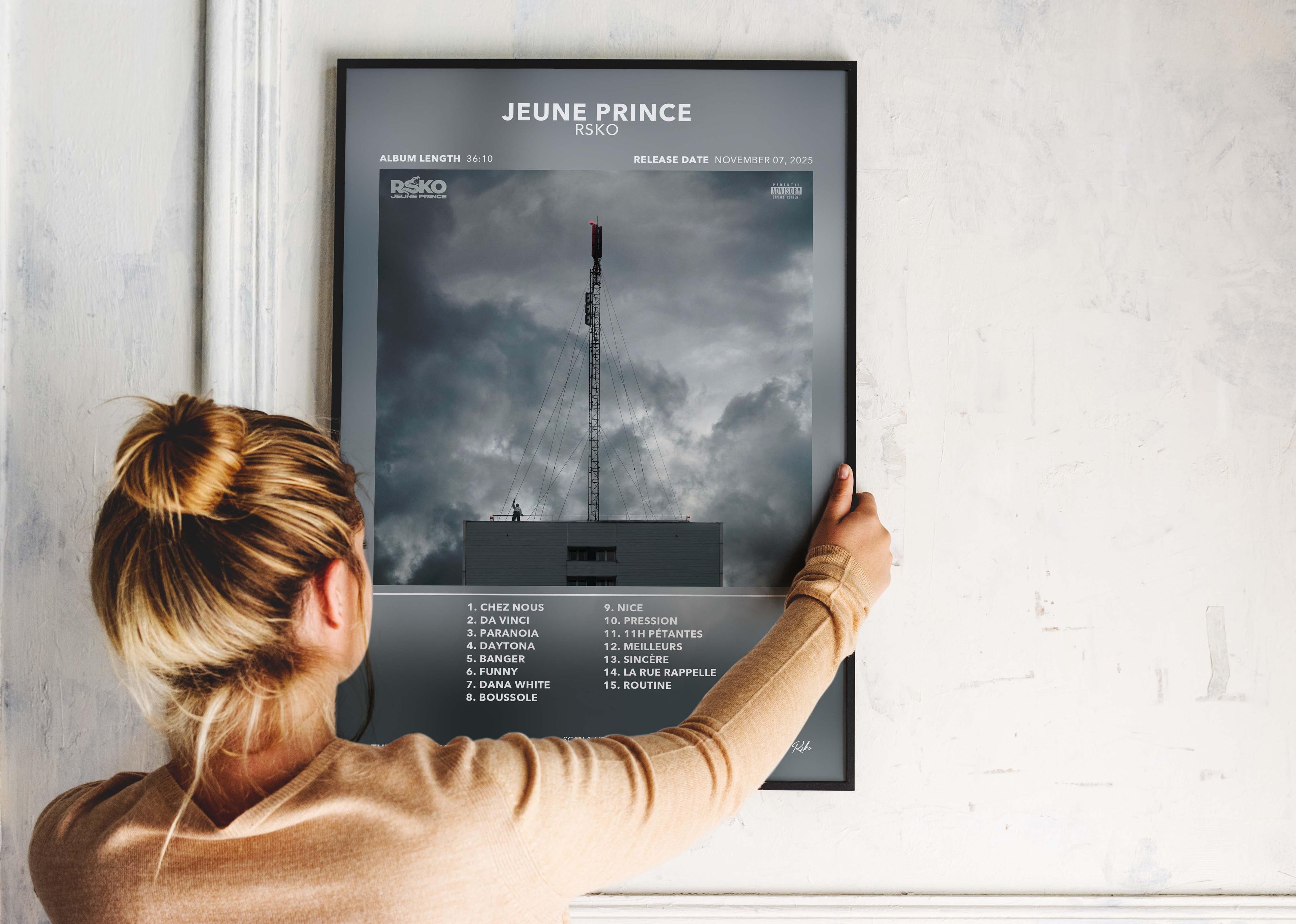Femme accrochant affiche album Jeune Prince de RSKO avec ciel nuageux, fait en France, livraison gratuite 48h