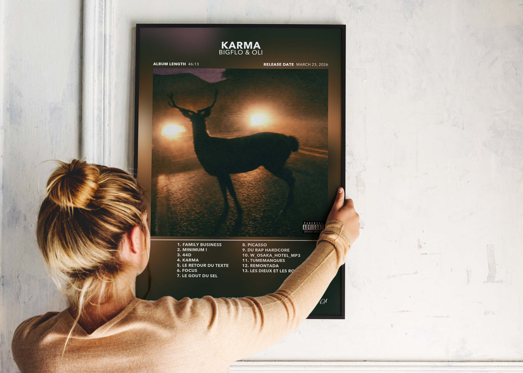 Une personne installe le poster encadré de Bigflo et Oli Karma sur un mur blanc de salon.