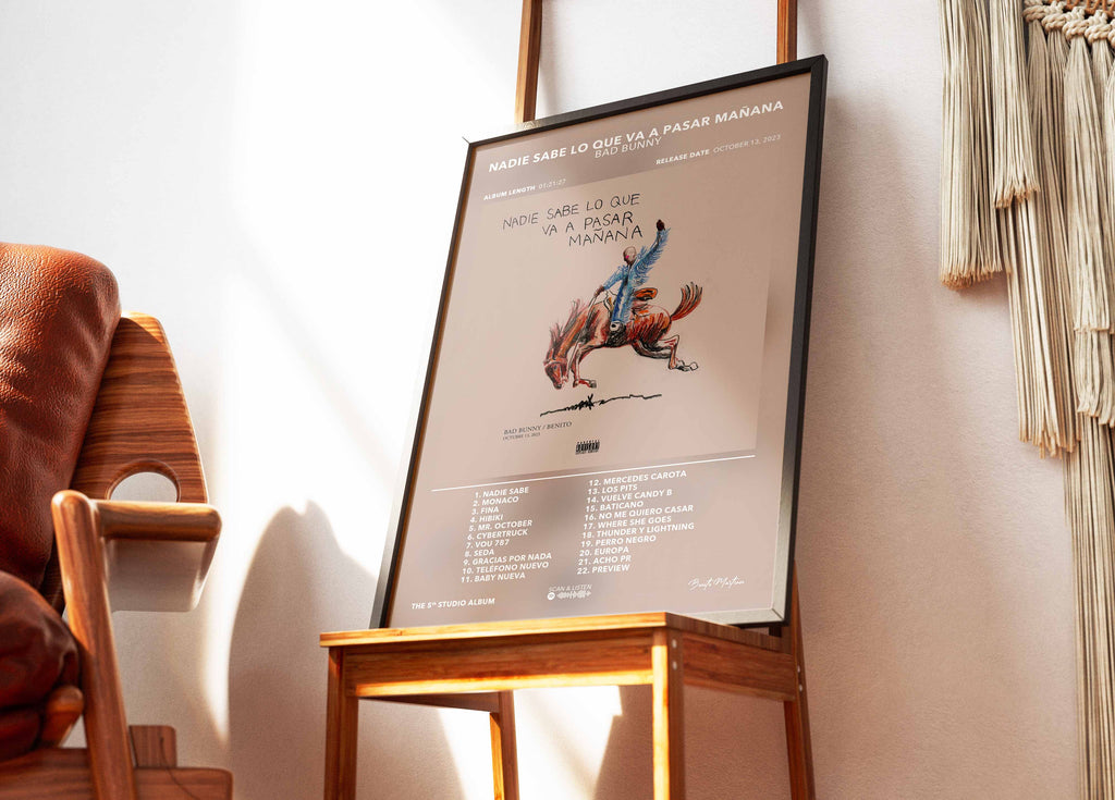Cadre contenant l'affiche de l'album Nadie Sabe Lo Que Va A Pasar Mañana de Bad Bunny posé sur une chaise design dans un salon moderne.