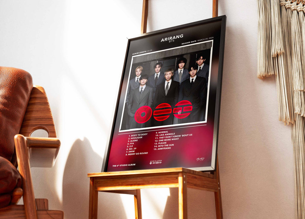 Cadre contenant l'affiche de l'album studio coréen Arirang de BTS posé sur une chaise design dans un salon lumineux.